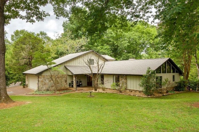  - view of front facade with a front yard, an attached garage, concrete driveway, and stone siding