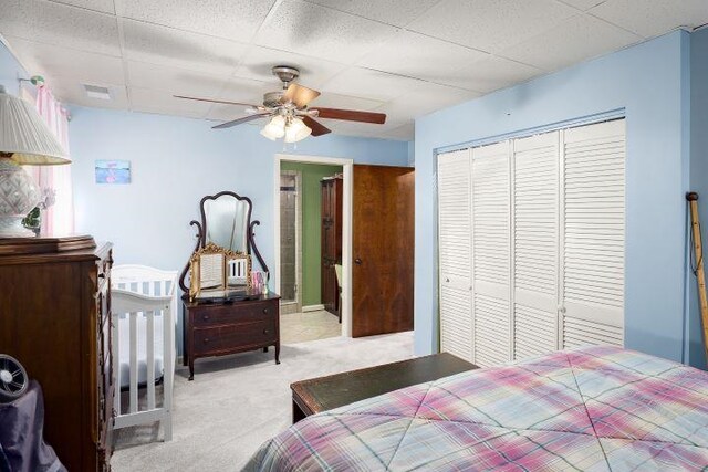  - bedroom featuring light colored carpet, a closet, a drop ceiling, a ceiling fan, and ensuite bath