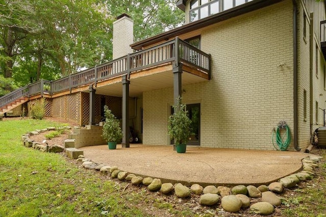  - rear view of property featuring brick siding, a deck, stairs, a patio area, and a chimney