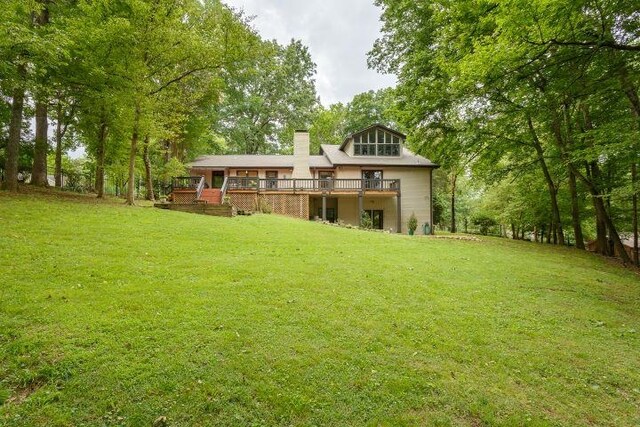  - rear view of property with a deck, a lawn, and a chimney