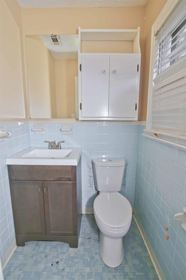 bathroom with vanity, tile walls, and toilet