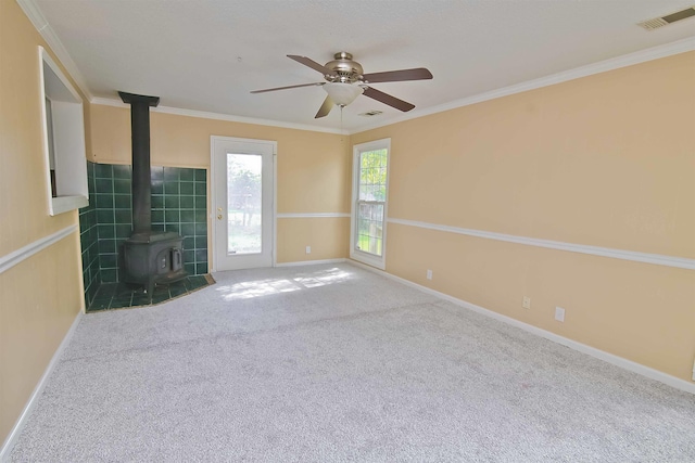 unfurnished living room featuring carpet, ornamental molding, ceiling fan, and a wood stove