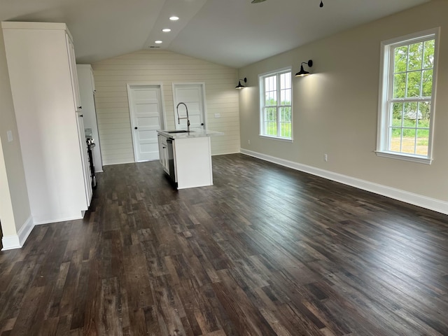 unfurnished living room featuring vaulted ceiling, plenty of natural light, dark wood-type flooring, and sink