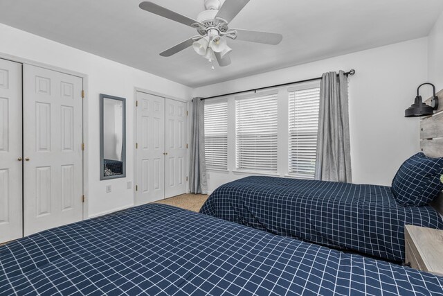 carpeted bedroom with ceiling fan and two closets