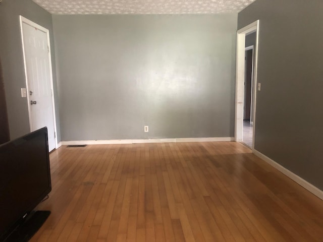 spare room with hardwood / wood-style floors and a textured ceiling