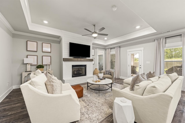  - living area with a raised ceiling, ceiling fan, dark wood finished floors, ornamental molding, and recessed lighting