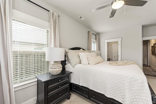  - bedroom with light carpet, a ceiling fan, baseboards, and connected bathroom