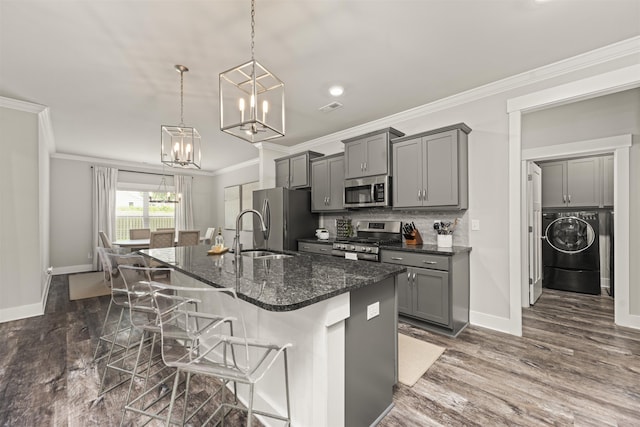  - kitchen with appliances with stainless steel finishes, gray cabinetry, washer / dryer, a sink, and ornamental molding