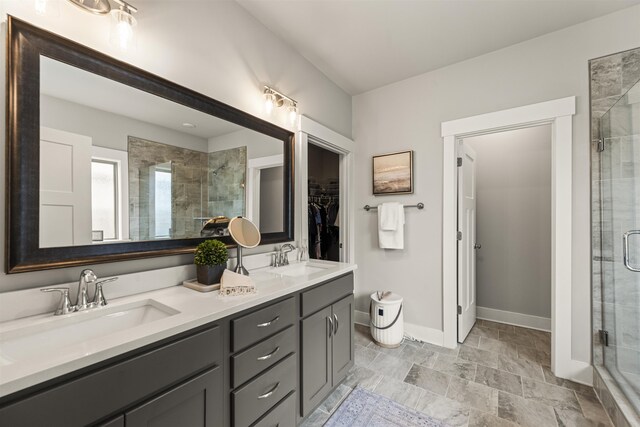  - bathroom featuring a shower stall, double vanity, baseboards, and a spacious closet