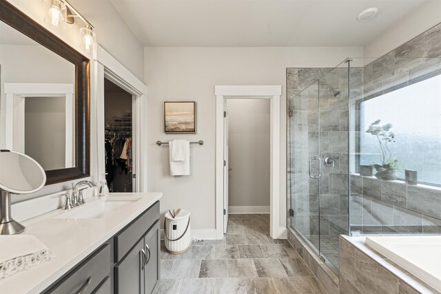  - bathroom featuring vanity, a shower stall, a garden tub, baseboards, and a walk in closet