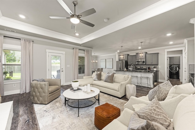  - living room featuring washer / clothes dryer, ornamental molding, dark wood-style floors, baseboards, and a ceiling fan