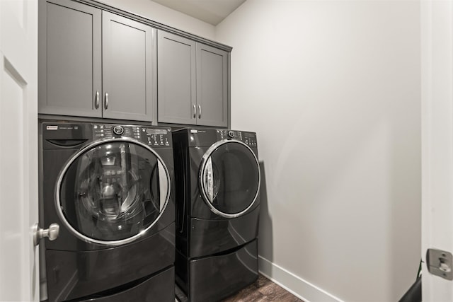  - laundry room featuring washing machine and clothes dryer, cabinet space, and dark wood-style floors