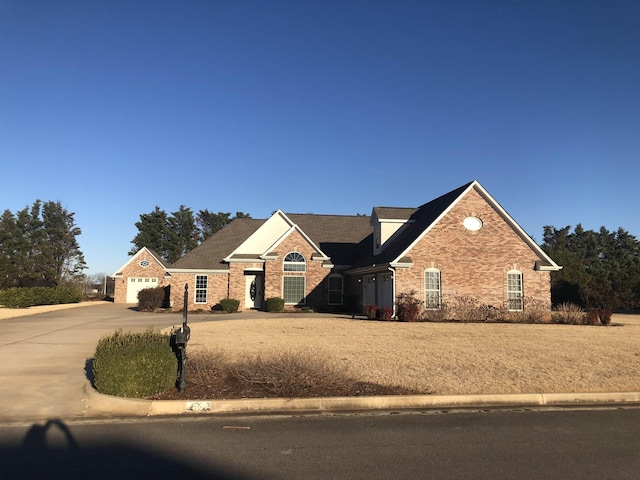 view of front of house with a garage, brick siding, and driveway