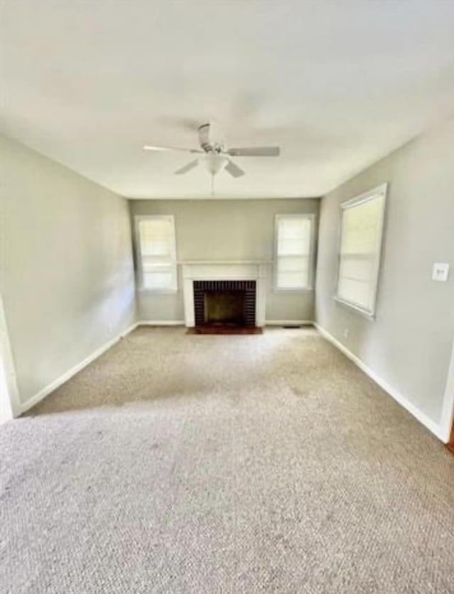 unfurnished living room with carpet floors, a brick fireplace, ceiling fan, and a healthy amount of sunlight