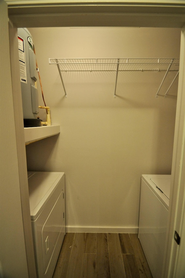 clothes washing area with dark wood-style floors, laundry area, washing machine and dryer, and baseboards