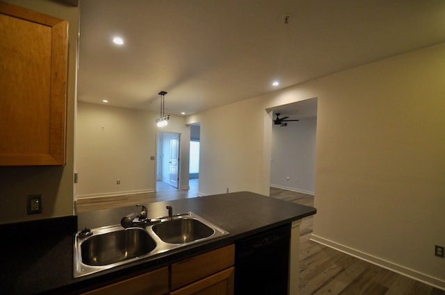 kitchen with a sink, black dishwasher, dark countertops, open floor plan, and dark wood finished floors