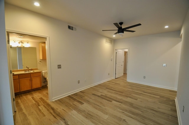 bedroom featuring ensuite bath, visible vents, light wood finished floors, and a sink