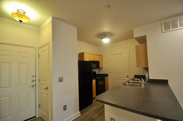 kitchen with visible vents, dark wood finished floors, a sink, black appliances, and dark countertops