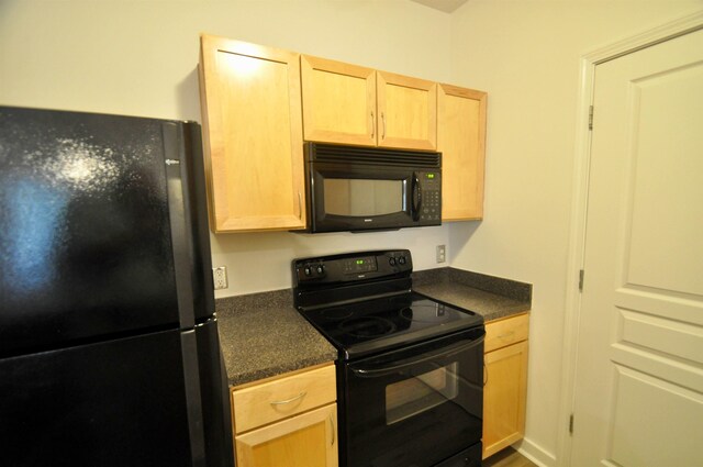 kitchen featuring dark countertops, black appliances, and light brown cabinets