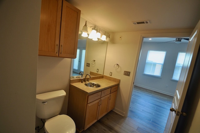 bathroom featuring vanity, wood finished floors, visible vents, baseboards, and toilet