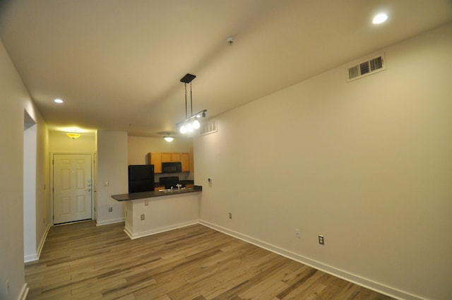 kitchen with black appliances, wood finished floors, a peninsula, and visible vents