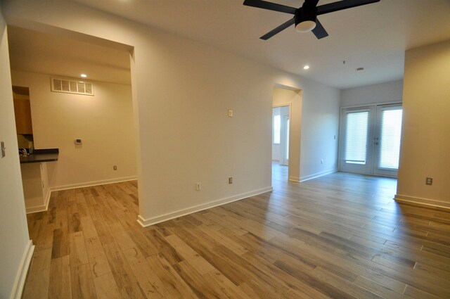 spare room featuring ceiling fan, visible vents, baseboards, and wood finished floors