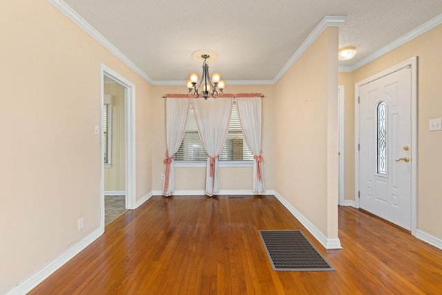 interior space with a chandelier, visible vents, ornamental molding, and hardwood / wood-style floors