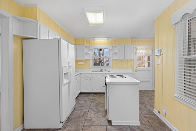 kitchen featuring a center island, light countertops, white fridge with ice dispenser, open shelves, and a sink