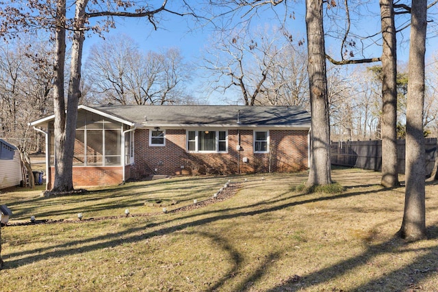 view of front of house with a sunroom, fence, brick siding, and a front yard