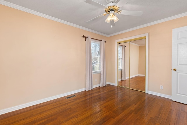 unfurnished bedroom with baseboards, visible vents, ornamental molding, hardwood / wood-style floors, and a closet