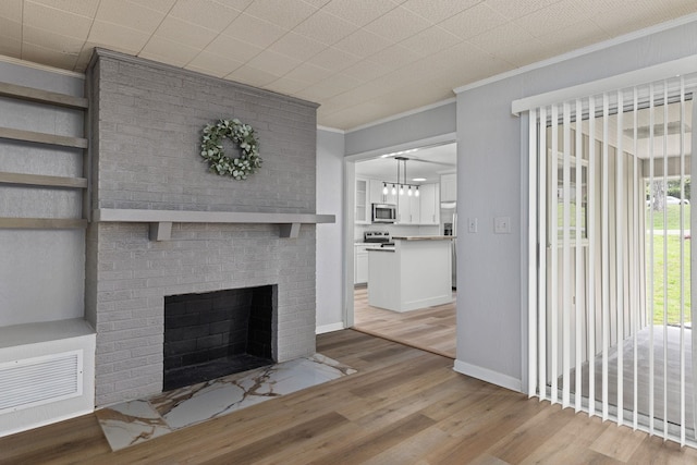 unfurnished living room featuring crown molding, light wood finished floors, a fireplace, and baseboards