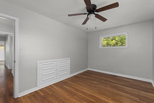 spare room featuring dark wood-style floors, baseboards, and a ceiling fan