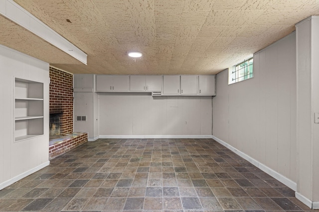 basement with a fireplace, built in shelves, baseboards, and wood walls