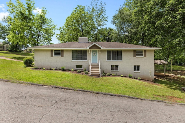 single story home with a front yard, brick siding, and a chimney