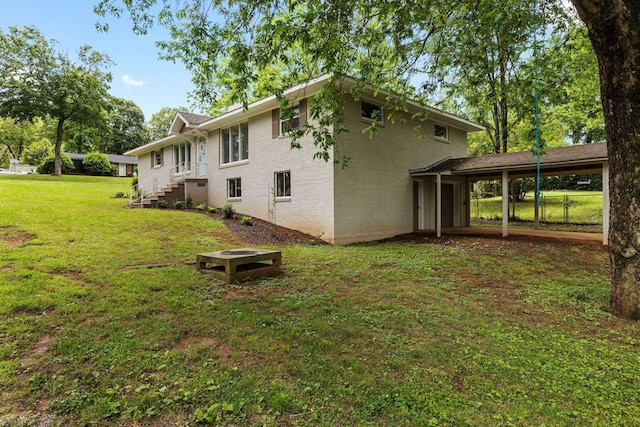 rear view of property featuring brick siding, a yard, and a carport