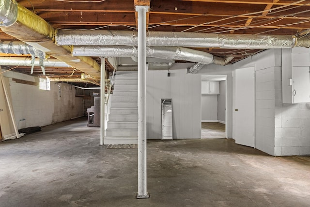 basement with stairs and concrete block wall