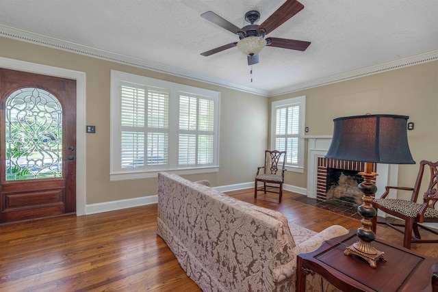  - living room featuring ornamental molding, a ceiling fan, wood finished floors, a fireplace, and a textured ceiling