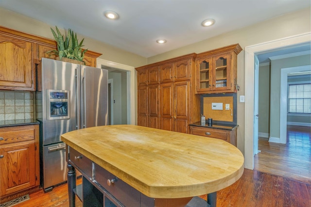  - kitchen featuring stainless steel fridge, brown cabinetry, decorative backsplash, baseboards, and recessed lighting