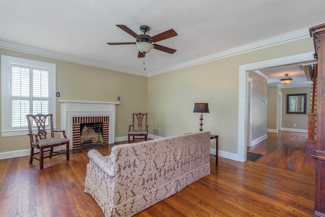  - living room featuring ceiling fan, wood finished floors, a fireplace, crown molding, and baseboards