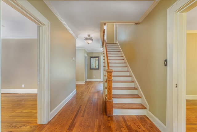  - stairway featuring wood finished floors, baseboards, and ornamental molding