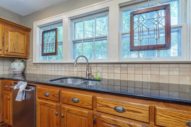  - kitchen featuring a sink, brown cabinets, dark countertops, and tasteful backsplash