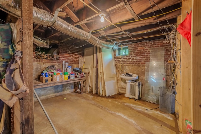  - basement featuring brick wall and radiator heating unit