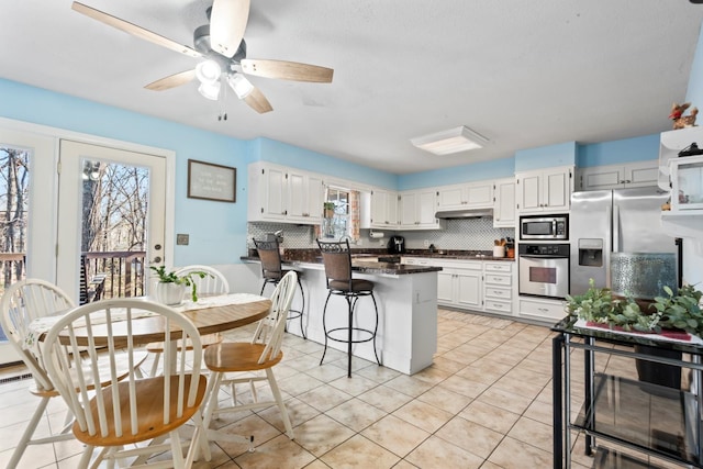 kitchen with appliances with stainless steel finishes, backsplash, white cabinetry, and a wealth of natural light