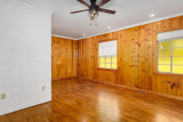 spare room with crown molding, hardwood / wood-style floors, and wood walls