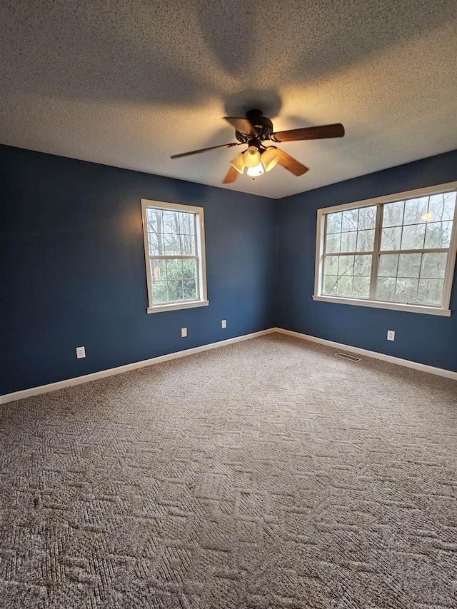 carpeted spare room featuring a textured ceiling and ceiling fan