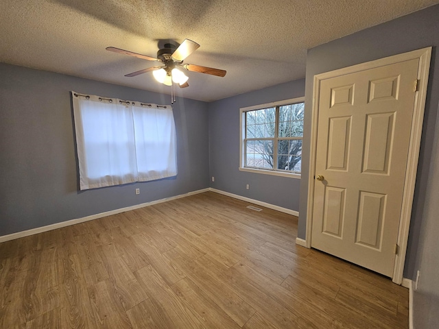 unfurnished bedroom featuring ceiling fan, a textured ceiling, and light hardwood / wood-style floors