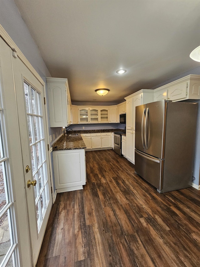 kitchen with dark hardwood / wood-style floors, dark stone countertops, sink, white cabinetry, and appliances with stainless steel finishes