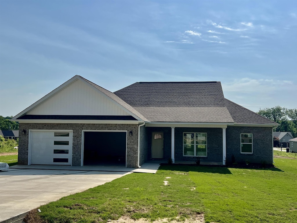 view of front of home with brick siding, an attached garage, driveway, and a front yard