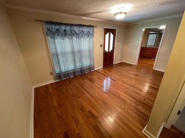 foyer entrance with hardwood / wood-style floors, crown molding, and a textured ceiling