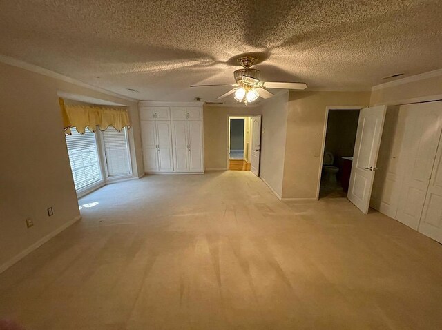 spare room with ceiling fan, crown molding, light colored carpet, and a textured ceiling